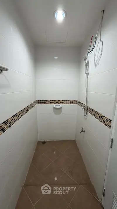 Compact bathroom with tiled walls and shower fixture, ideal for small spaces.