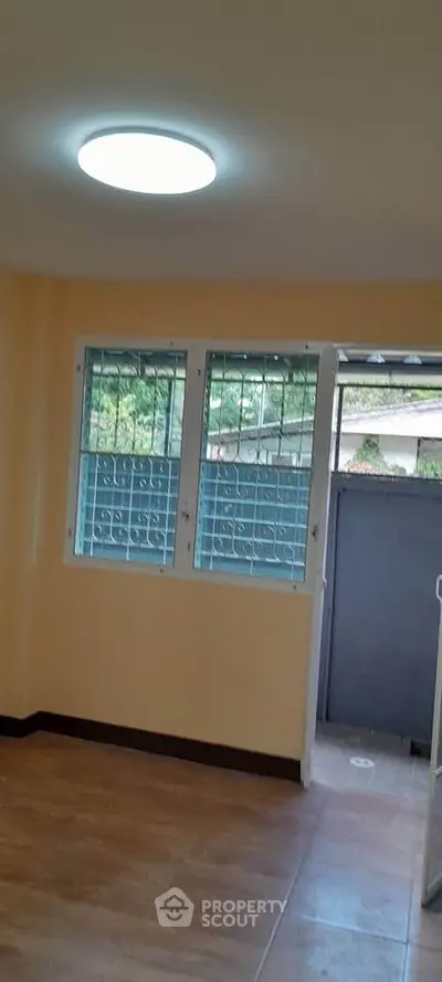 Bright room with large windows and secure metal grills, opening to a garden view.