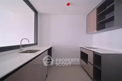 Modern kitchen with sleek cabinetry and minimalist design, featuring a large window for natural light.