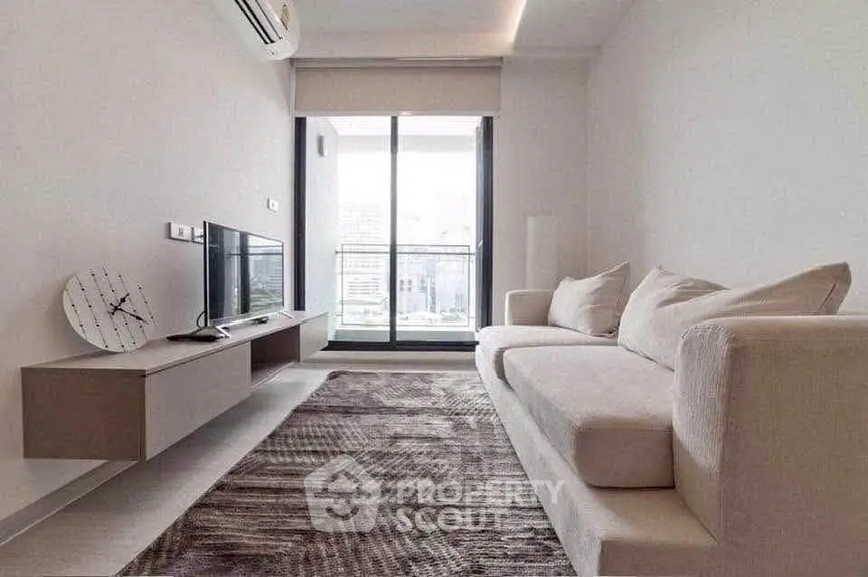 Modern living room with sleek furniture and large window offering city view.