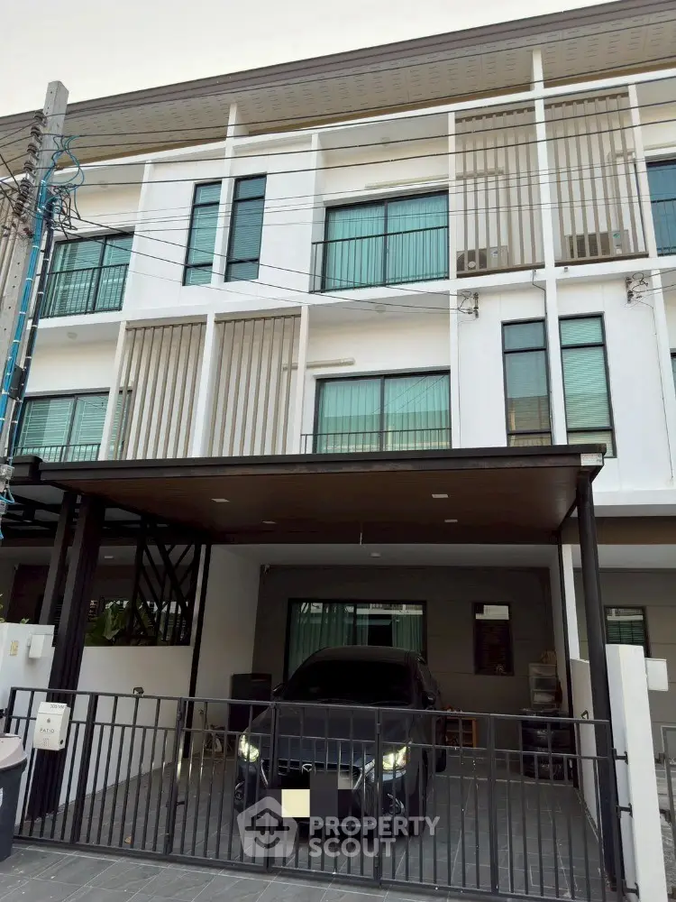 Modern three-story townhouse with gated parking and sleek facade.