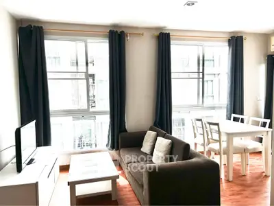 Bright living room with large windows, modern sofa, and dining area in a stylish apartment.