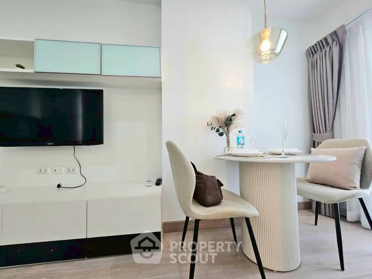 Modern living room with stylish dining area and wall-mounted TV in a bright apartment.