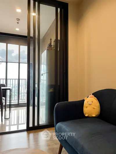Modern living room with plush sofa and sliding glass doors leading to a balcony with city view.
