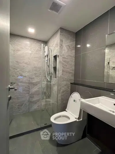 Modern bathroom with sleek design, featuring a glass shower enclosure and contemporary fixtures.