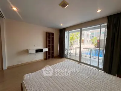 Spacious bedroom with pool view and large windows in modern apartment