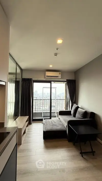 Modern living room with large windows and city view, featuring a stylish sofa and sleek decor.
