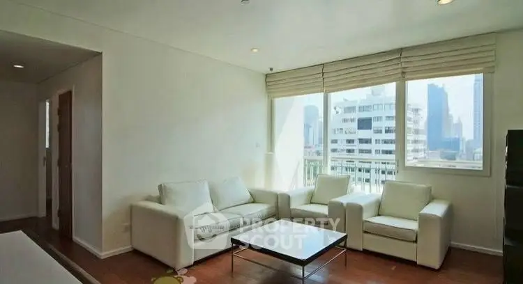 Spacious modern living room with city view and elegant white furniture.