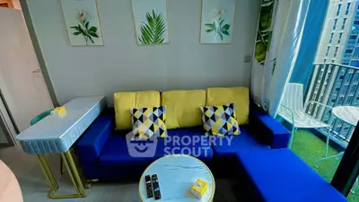 Modern living room with vibrant blue and yellow decor, featuring a cozy sofa and balcony view.