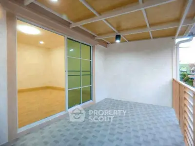 Spacious balcony with sliding glass doors and wooden railing, perfect for relaxation.