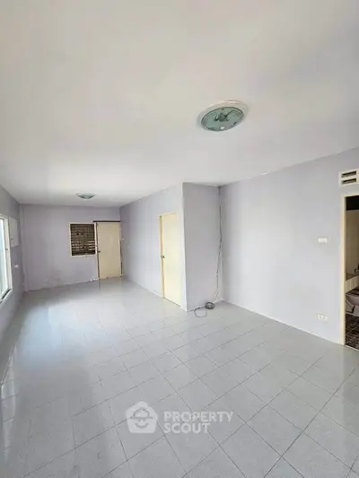 Spacious empty room with tiled flooring and neutral walls, ready for customization.
