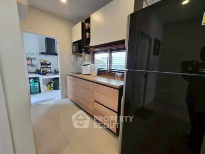 Modern kitchen with sleek cabinets and large fridge, featuring open layout and ample natural light.
