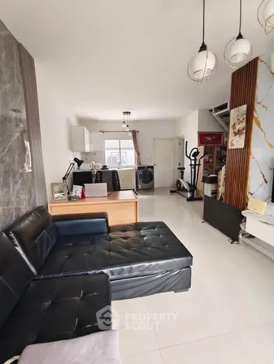 Modern living room with sleek black leather sofa and open kitchen layout
