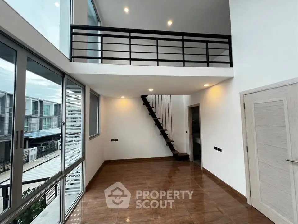 Modern duplex interior with mezzanine and large windows offering ample natural light.
