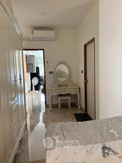 Charming bedroom with elegant vanity and wardrobe, featuring polished floors and air conditioning.