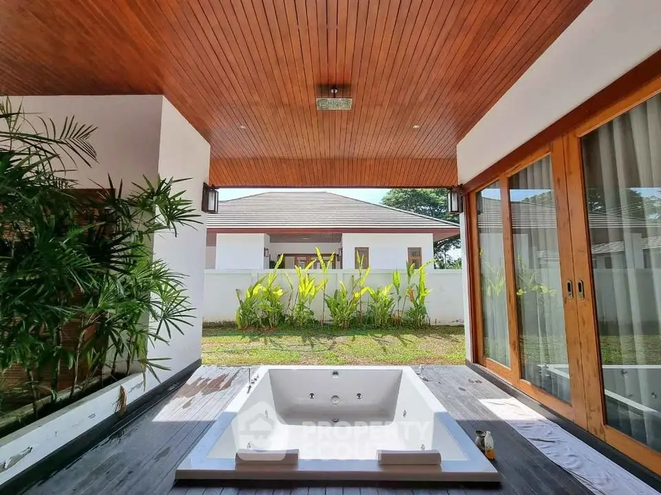 Luxurious outdoor jacuzzi area with wooden ceiling and garden view