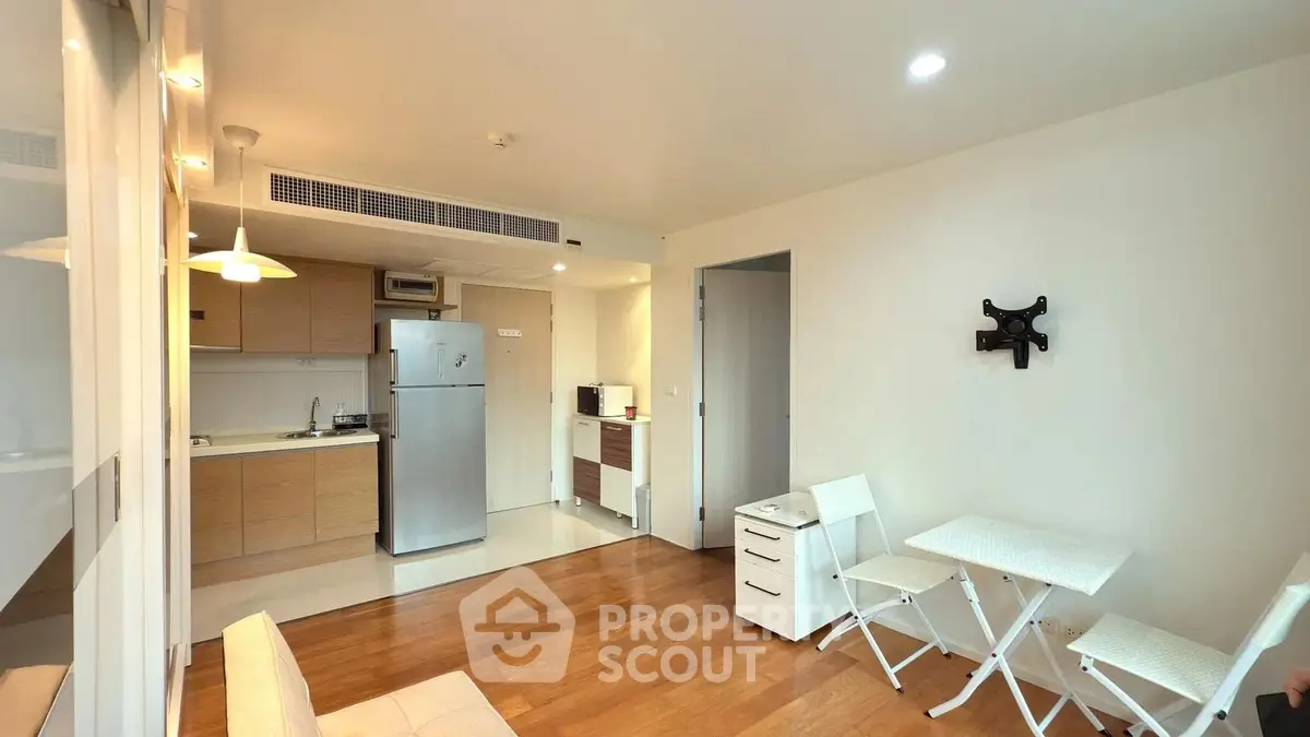 Modern open-layout kitchen and living area with wooden flooring and compact dining setup.