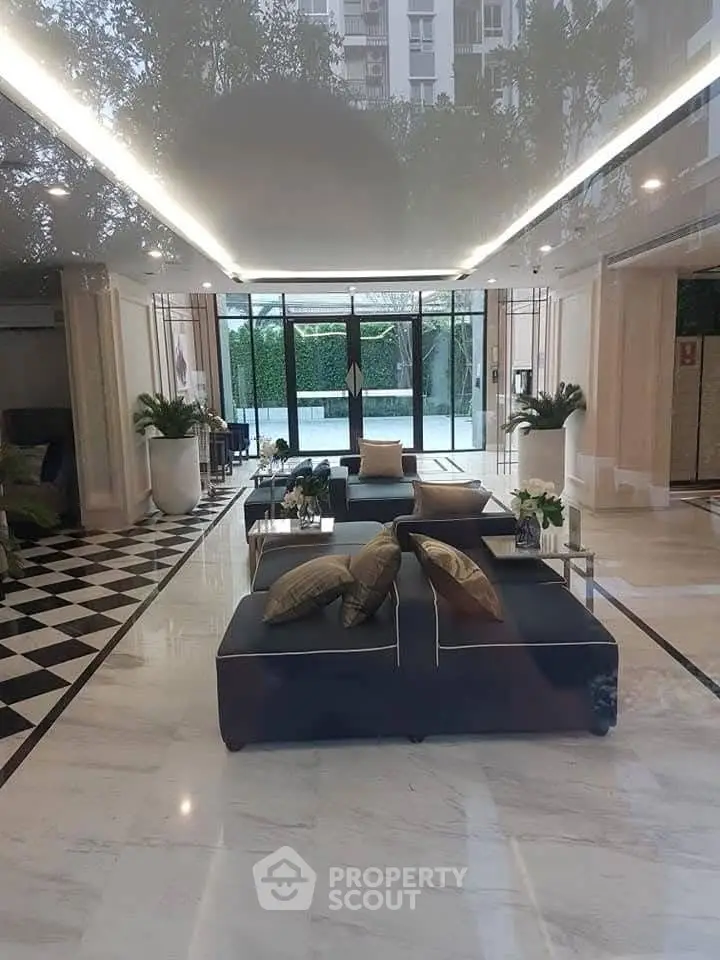 Luxurious modern lobby with elegant seating and marble flooring, featuring floor-to-ceiling windows and lush greenery.