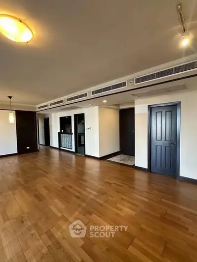 Spacious modern living room with wooden flooring and elegant lighting in a luxury apartment.