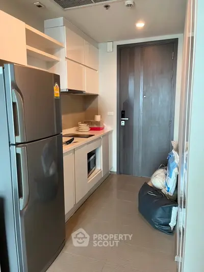 Modern compact kitchen with sleek appliances and ample storage in a stylish apartment.