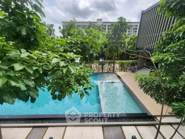 Luxurious pool area surrounded by lush greenery in a modern residential complex.