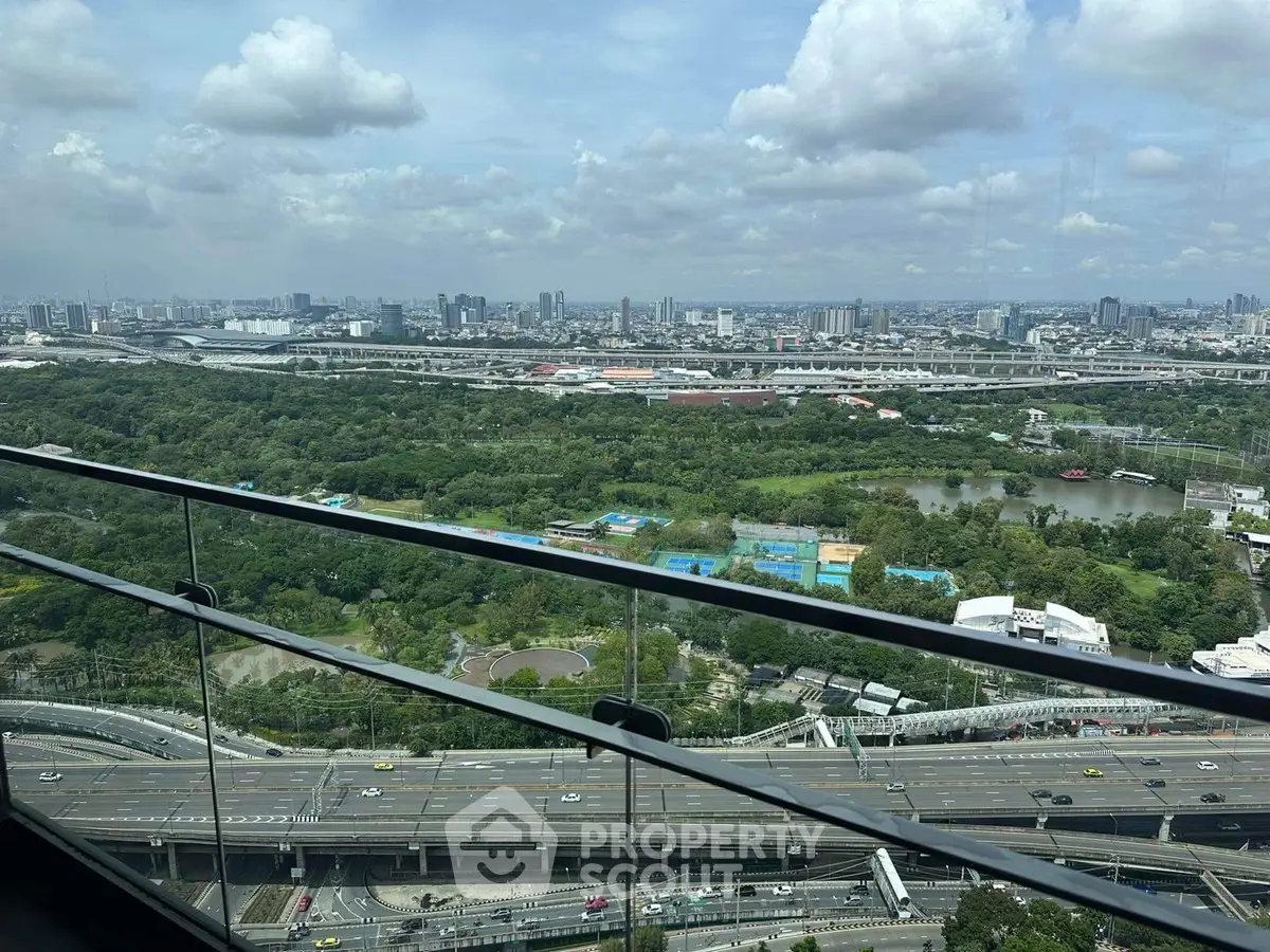 Stunning cityscape view from high-rise balcony overlooking lush greenery and urban skyline.