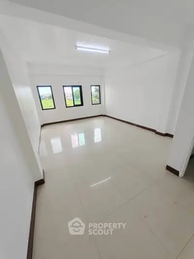 Spacious empty room with large windows and tiled flooring, offering potential for customization.