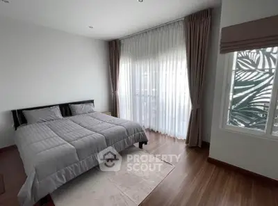 Spacious bedroom with elegant curtains and wooden flooring, perfect for a cozy retreat.