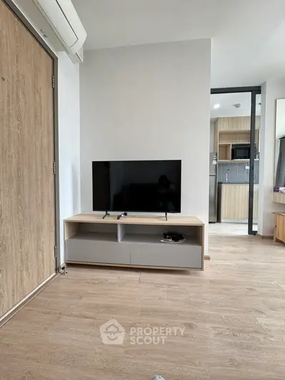 Modern living room with sleek TV stand and open kitchen layout, perfect for contemporary living.