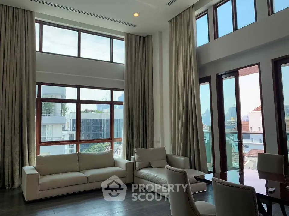 Luxurious high-ceiling living room with large windows and elegant furnishings