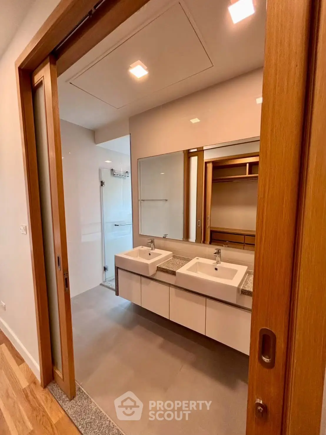 Modern bathroom with dual sinks and wooden sliding doors in a stylish apartment.