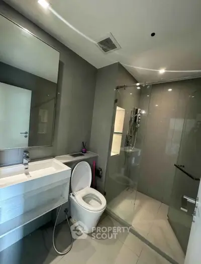 Modern bathroom with sleek design, featuring a glass shower enclosure and contemporary fixtures.