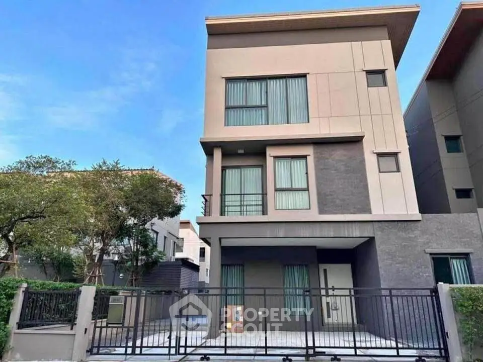Modern three-story house with sleek design and gated entrance in a serene neighborhood.