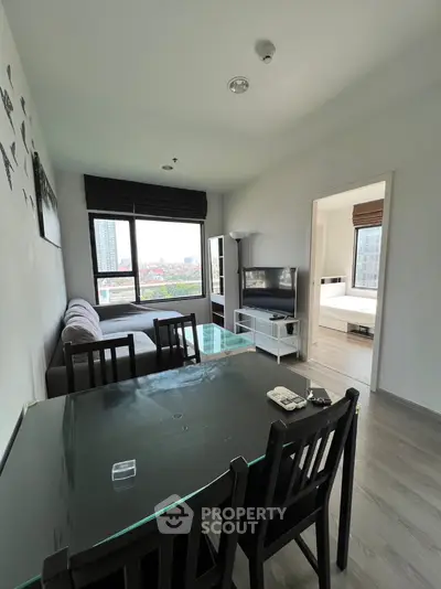 Modern living room with dining area and city view, featuring sleek furniture and large windows.