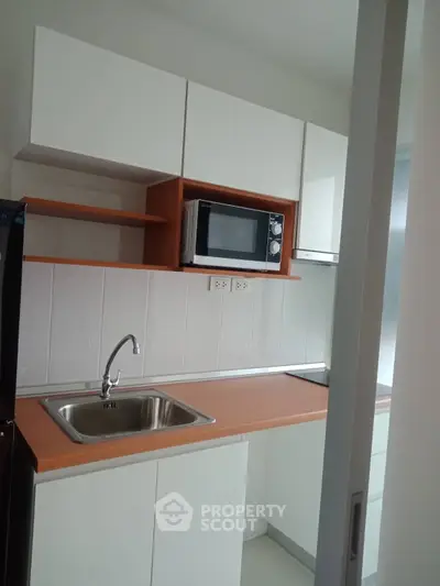 Modern kitchen with sleek cabinetry and built-in microwave, featuring a stylish sink and ample counter space.