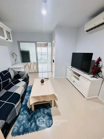 Modern living room with stylish decor and large TV, featuring a cozy sofa and elegant coffee table.