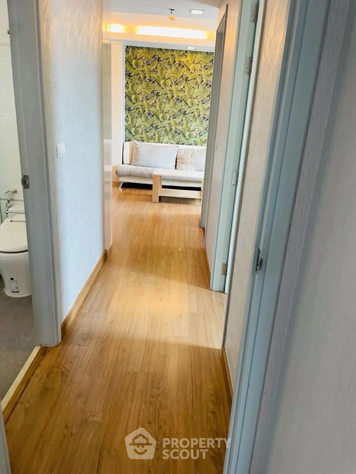 Bright hallway leading to a stylish living room with modern decor and wooden flooring.