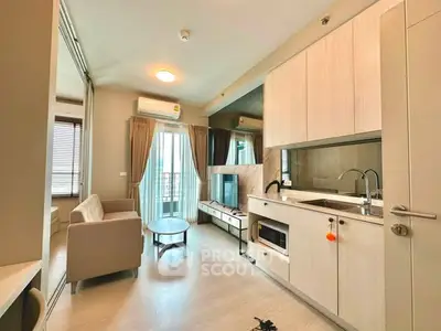 Modern open-layout living room with kitchen, featuring sleek cabinetry and natural light.