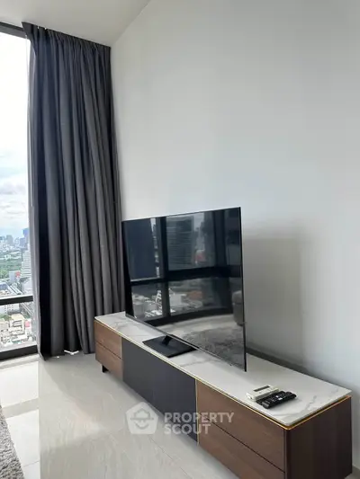 Modern living room with sleek TV setup and panoramic city view, perfect for urban living.