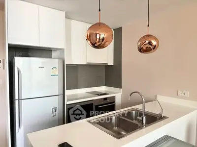 Modern kitchen with sleek design, featuring stainless steel appliances and stylish pendant lights.