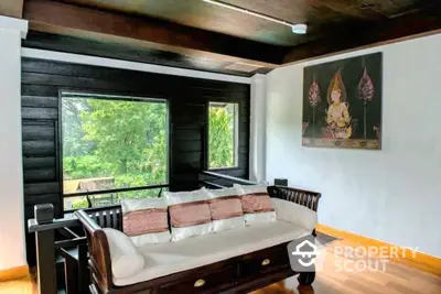 Charming living room with polished wooden floors, dark wood accents, and a serene nature view through large windows, complemented by traditional artwork.