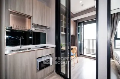 Modern kitchen with sleek cabinetry and open layout leading to a bright dining area and balcony.
