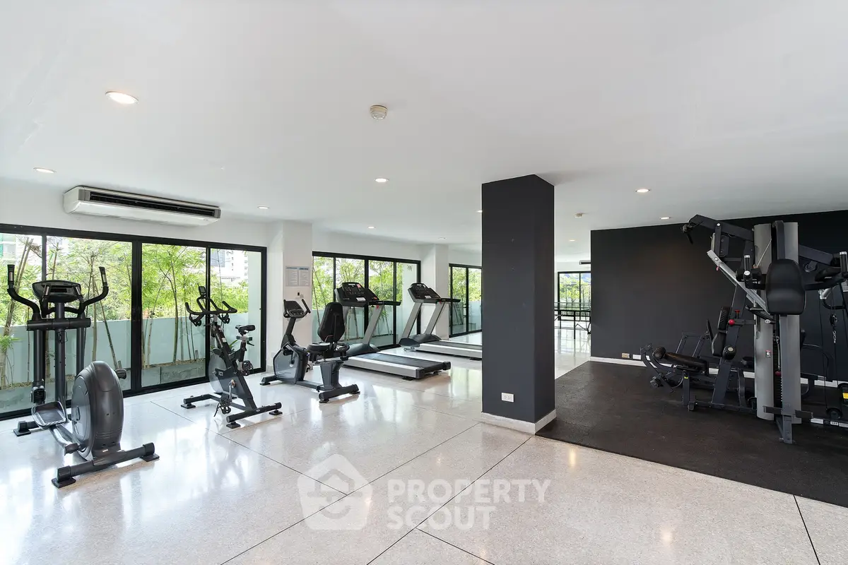 Spacious modern gym with large windows and state-of-the-art equipment in a luxury residential building.