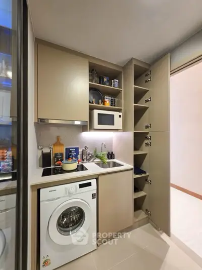 Modern compact kitchen with washing machine and microwave, efficient storage solutions.
