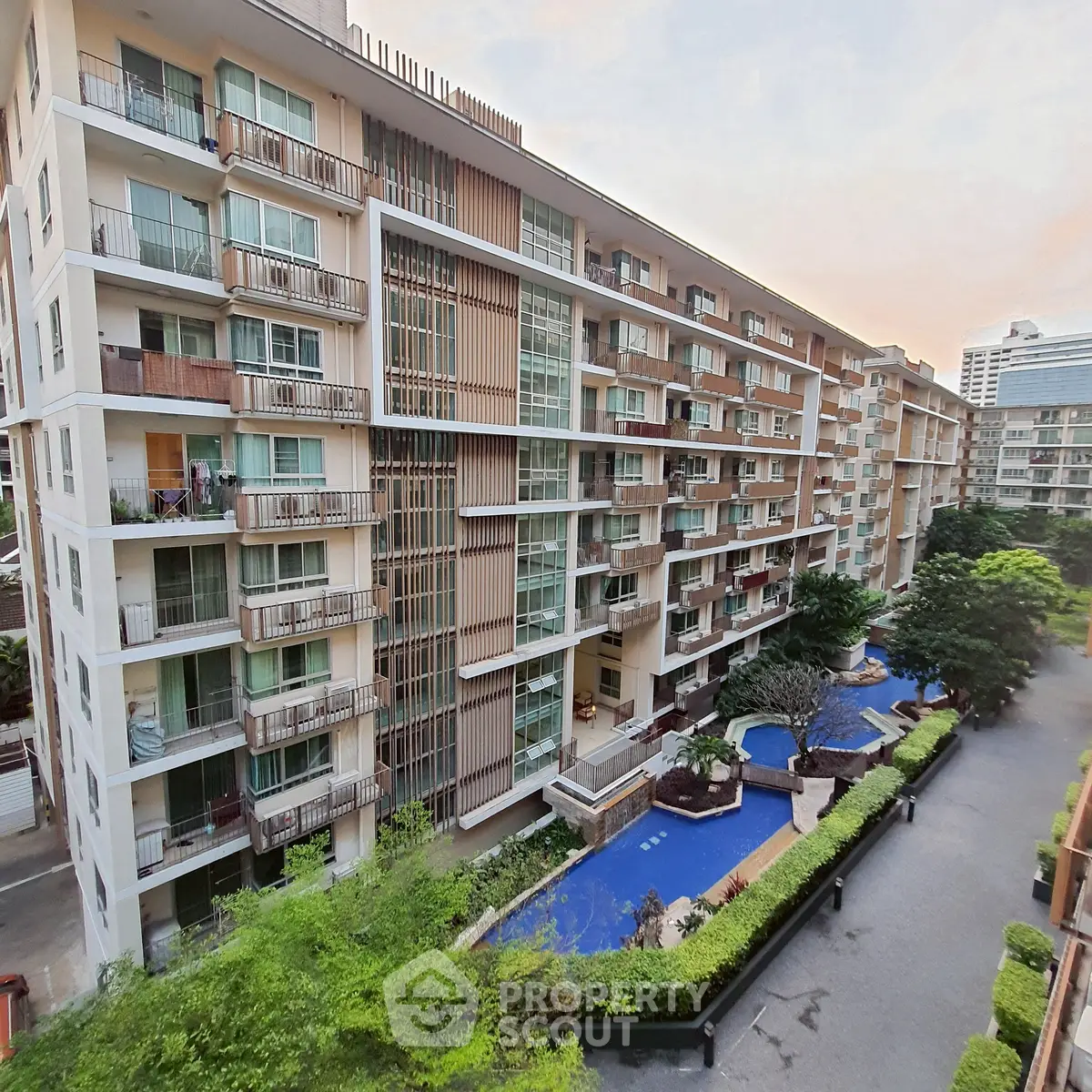 Modern condominium building with pool and lush greenery in urban setting