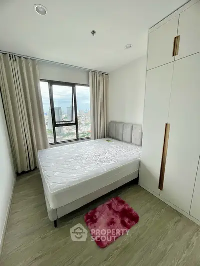 Modern bedroom with large window offering stunning city views, featuring a comfortable bed and spacious wardrobe.