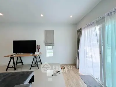 Modern living room with sleek TV setup and natural light from large windows.