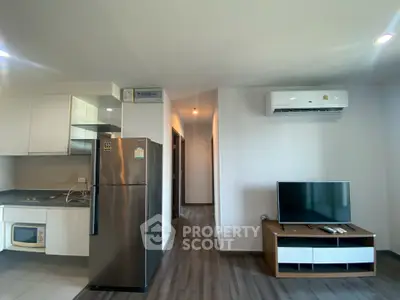 Modern apartment interior with sleek kitchen and cozy living area featuring air conditioning and flat-screen TV.