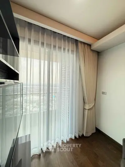 Modern apartment corner with floor-to-ceiling windows and elegant curtains offering a stunning city view.