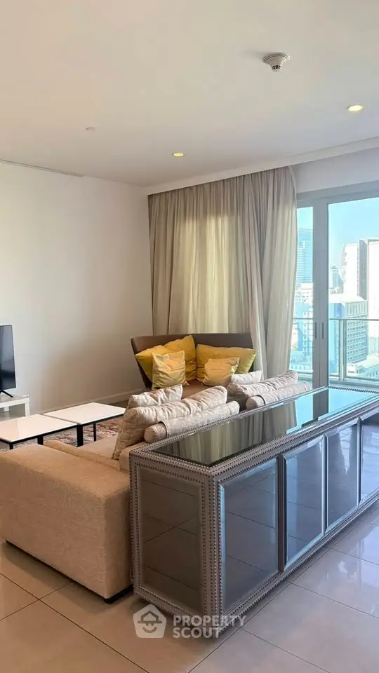 Spacious living room with modern decor and city view, featuring a cozy sofa and elegant furnishings.